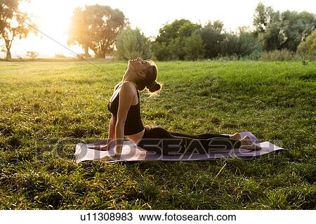 Young woman practicing yoga in park at sunset View Large Photo Image Stock Image - Young woman practicing yoga in park at sunset. Fotosearch