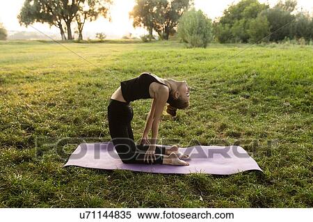 Stock Photography - Young woman practicing yoga in park. Fotosearch