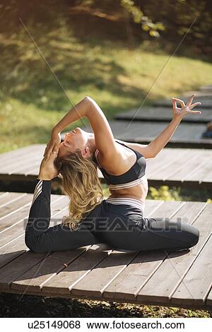 Stock Photo - Young woman practicing yoga on boardwalk. Fotosearch