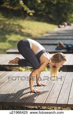 Stock Photography - Young woman practicing yoga on boardwalk. Fotosearch