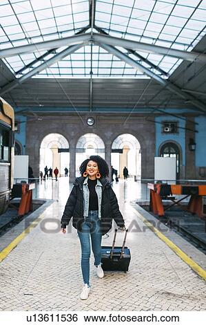 Young woman pulling suitcase in railway station View Large Photo Image Stock Photograph - Young woman pulling suitcase in railway station. Fotosearch
