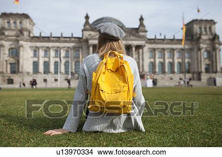 Picture - Young woman sitting in park by Reichstag in Berlin, Germany. Fotosearch