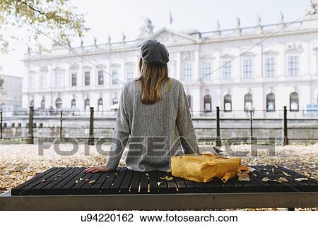 Stock Image - Young woman sitting on park bench near German Historical Museum in Berlin, Germany. Fotosearch