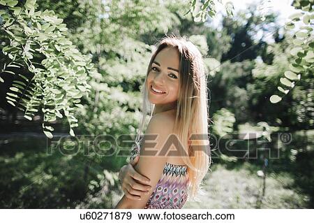 Young woman smiling in park View Large Photo Image Stock Photo - Young woman smiling in park. Fotosearch