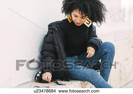 Young woman sorting photographs on bench View Large Photo Image Picture - Young woman sorting photographs on bench. Fotosearch