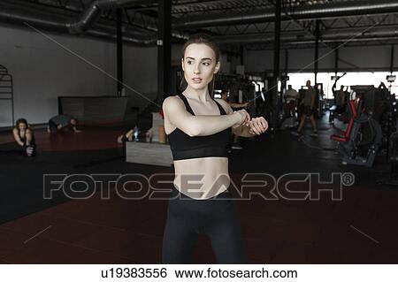 Young woman stretching in gym View Large Photo Image Stock Photograph - Young woman stretching in gym. Fotosearch