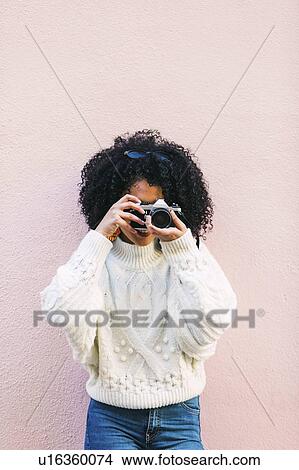 Young woman taking photograph against pink wall View Large Photo Image Picture - Young woman taking photograph against pink wall. Fotosearch