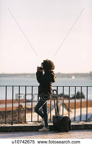Young woman taking photograph by railing View Large Photo Image Stock Photography - Young woman taking photograph by railing. Fotosearch