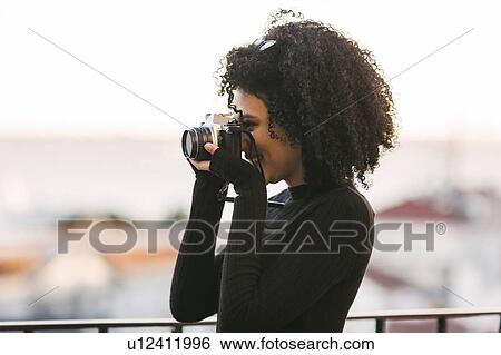 Young woman taking photograph View Large Photo Image Stock Photograph - Young woman taking photograph. Fotosearch