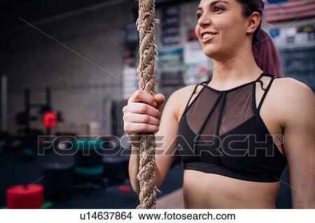 Picture - Young woman training, holding exercise rope in gym. Fotosearch
