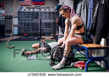 Young woman training, sitting on bench packing sports bag in gym View Large Photo Image Stock Image - Young woman training, sitting on bench packing sports bag in gym. Fotosearch