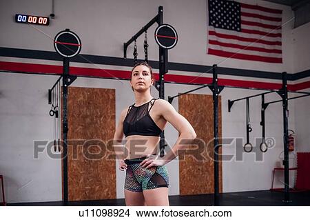 Young woman training, standing in gym with hands on hips View Large Photo Image Picture - Young woman training, standing in gym with hands on hips. Fotosearch