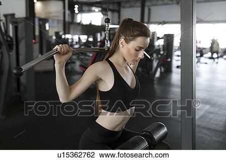 Young woman using exercise machine in gym View Large Photo Image Stock Image - Young woman using exercise machine in gym. Fotosearch