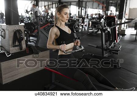 Young woman using exercise machine in gym View Large Photo Image Stock Image - Young woman using exercise machine in gym. Fotosearch