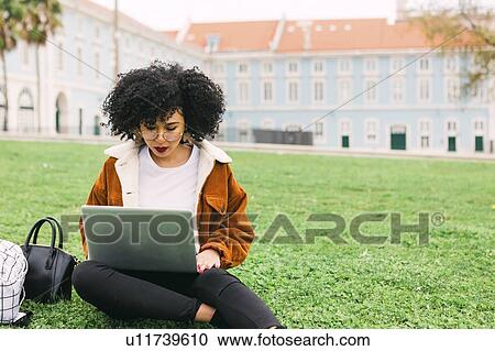 Young woman using laptop in park View Large Photo Image Stock Image - Young woman using laptop in park. Fotosearch