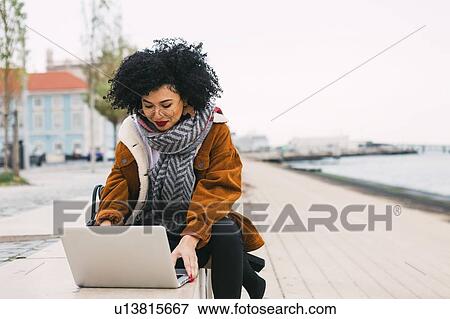 Young woman using laptop on waterfront in Lisbon, Portugal View Large Photo Image Stock Photo - Young woman using laptop on waterfront in Lisbon, Portugal. Fotosearch