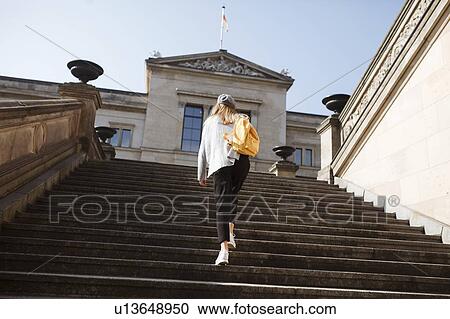 Stock Image - Young woman walking on steps in Berlin, Germany. Fotosearch