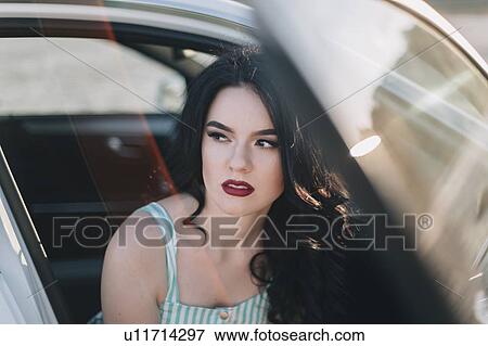Stock Photo - Young woman wearing red lipstick sitting in car. Fotosearch