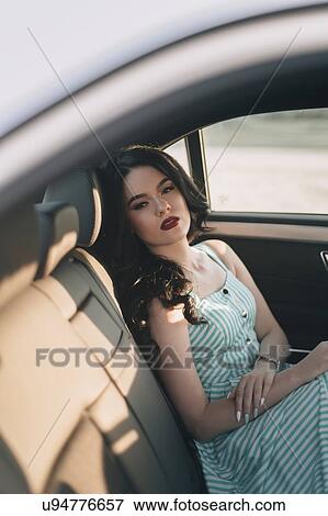 Young woman wearing striped dress sitting in car View Large Photo Image Stock Photo - Young woman wearing striped dress sitting in car. Fotosearch