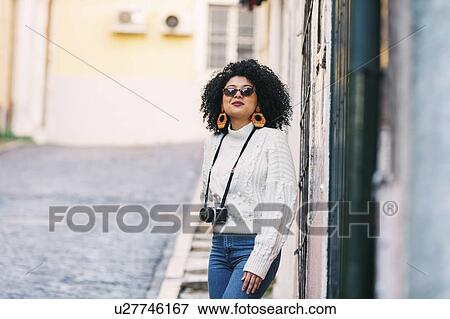 Young woman wearing sunglasses with camera on street View Large Photo Image Stock Photo - Young woman wearing sunglasses with camera on street. Fotosearch