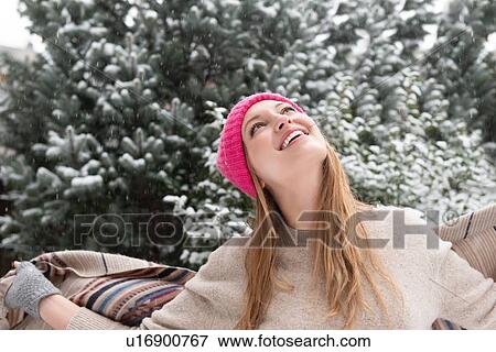 Young woman wearing woolly hat looking up in snow View Large Photo Image Stock Photo - Young woman wearing woolly hat looking up in snow. Fotosearch