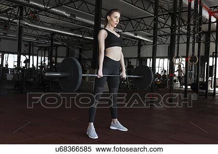 Stock Photography - Young woman weight lifting in gym. Fotosearch