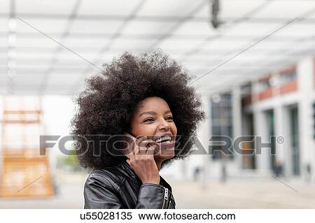 Young woman with afro hair at city train station, making smartphone call View Large Photo Image Stock Photography - Young woman with afro hair at city train station, making smartphone call. Fotosearch