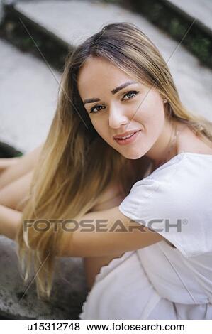 Stock Photo - Young woman with dyed blond hair sitting on steps. Fotosearch