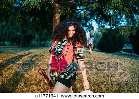 Stock Image - Young woman with guitar in park. Fotosearch