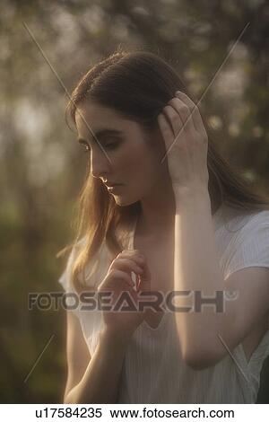 Stock Photography - Young woman with her hand in her brown hair. Fotosearch