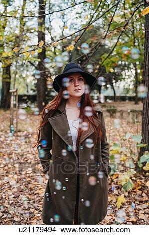 Young woman with long red hair amongst floating bubbles in autumn park, portrait View Large Photo Image Picture - Young woman with long red hair amongst floating bubbles in autumn park, portrait. Fotosearch