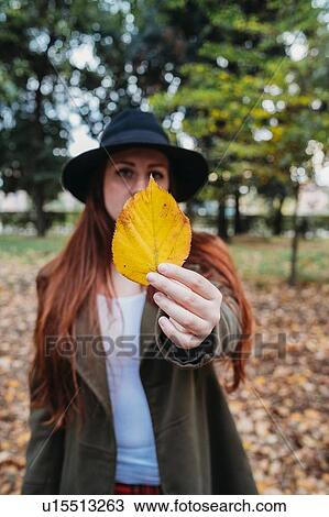Young woman with long red hair holding up autumn leaf in park, portrait View Large Photo Image Stock Image - Young woman with long red hair holding up autumn leaf in park, portrait. Fotosearch