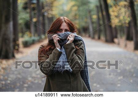Young woman with long red hair in autumn park covering mouth with scarf, portrait View Large Photo Image Stock Image - Young woman with long red hair in autumn park covering mouth with scarf, portrait. Fotosearch