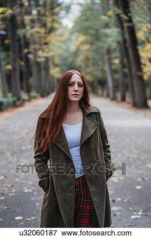 Stock Photo - Young woman with long red hair in autumn park, portrait. Fotosearch