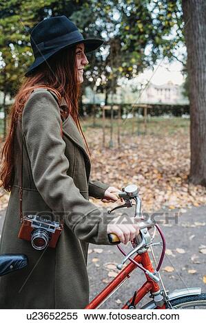 Young woman with long red hair pushing bicycle in autumn park View Large Photo Image Stock Photography - Young woman with long red hair pushing bicycle in autumn park. Fotosearch
