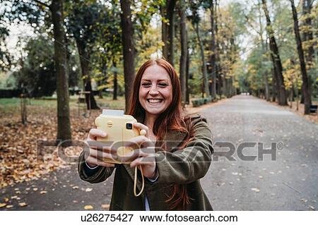 Young woman with long red hair taking instant selfie in autumn park View Large Photo Image Stock Photo - Young woman with long red hair taking instant selfie in autumn park. Fotosearch