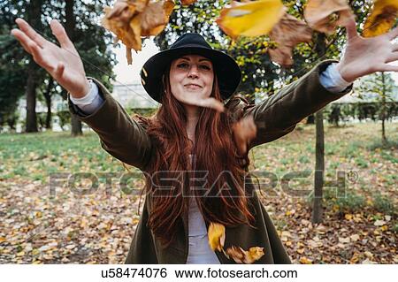 Young woman with long red hair throwing autumn leaves in park View Large Photo Image Stock Photograph - Young woman with long red hair throwing autumn leaves in park. Fotosearch