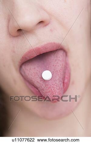 Stock Image - Young woman with pill on tongue.. Fotosearch