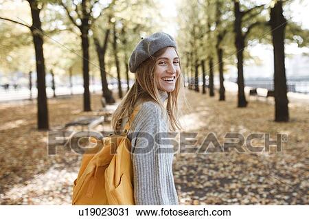 Stock Image - Young woman with yellow backpack in park in Berlin, Germany. Fotosearch