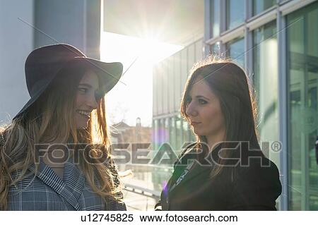 Stock Photography - Young women chatting outside sunlit office building, Turin, Piemonte, Italy. Fotosearch