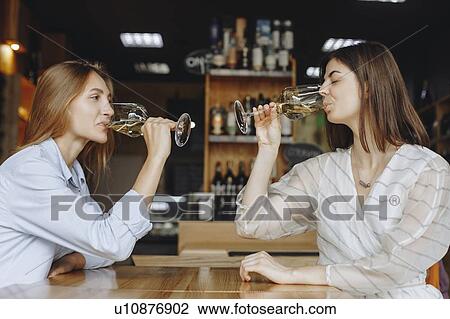 Stock Image - Young women drinking white wine. Fotosearch