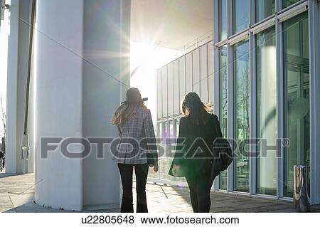 Stock Photo - Young women strolling outside office building, rear view, Turin, Piemonte, Italy. Fotosearch