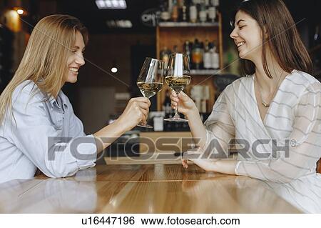 Stock Photograph - Young women toasting with glasses of white wine. Fotosearch