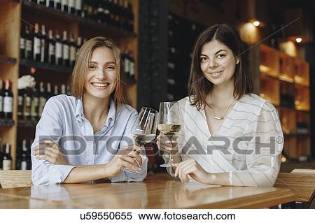 Young women toasting with glasses of white wine View Large Photo Image Stock Photography - Young women toasting with glasses of white wine. Fotosearch
