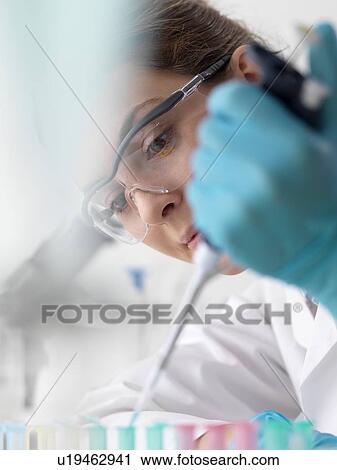 Stock Image - Biotechnology research. Scientist pipetting sample into a microcentrifuge tube ready for automated analysis.. Fotosearch