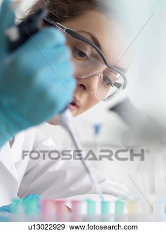 Stock Photo - Biotechnology research. Scientist pipetting sample into a microcentrifuge tube ready for automated analysis.. Fotosearch