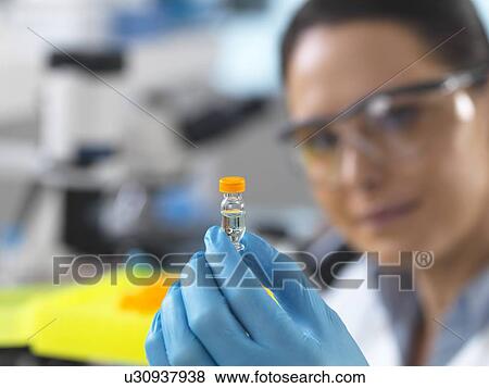 Stock Photo - Biotechnology research. Scientist examining sample in a test tube ready for automated analysis.. Fotosearch