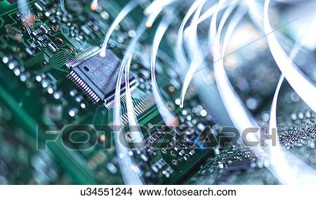 Picture - Digital communication, conceptual image. Fibre optics carrying data over electronic circuitry on a laptop computer.. Fotosearch