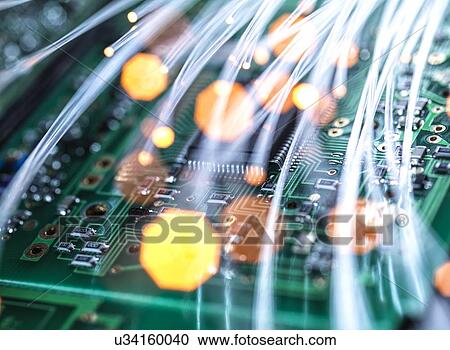 Stock Image - Digital communication, conceptual image. Fibre optics carrying data over electronic circuitry on a laptop computer.. Fotosearch