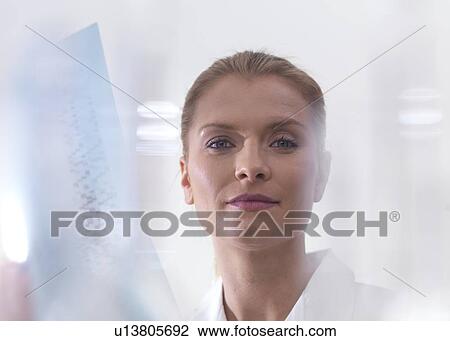 Stock Image - Genetics research. Scientist viewing DNA (deoxyribonucleic acid) results on a autoradiogram.. Fotosearch